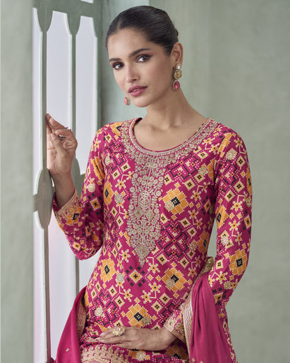 Woman wearing a pink and gold embroidered traditional outfit against a neutral background