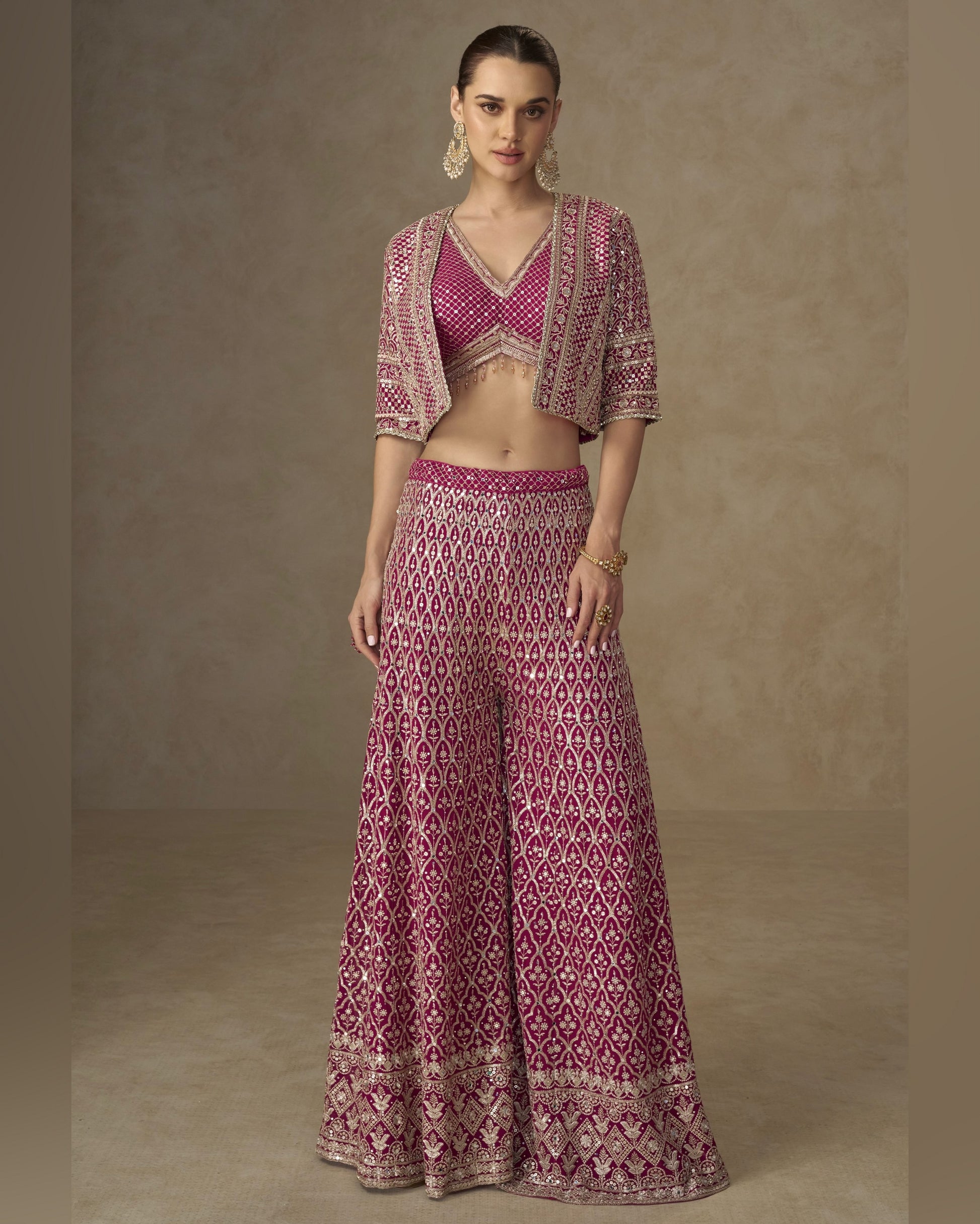 Woman wearing a patterned outfit with a top and long skirt against a neutral background