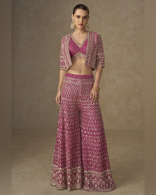 Woman wearing a patterned outfit with a top and long skirt against a neutral background