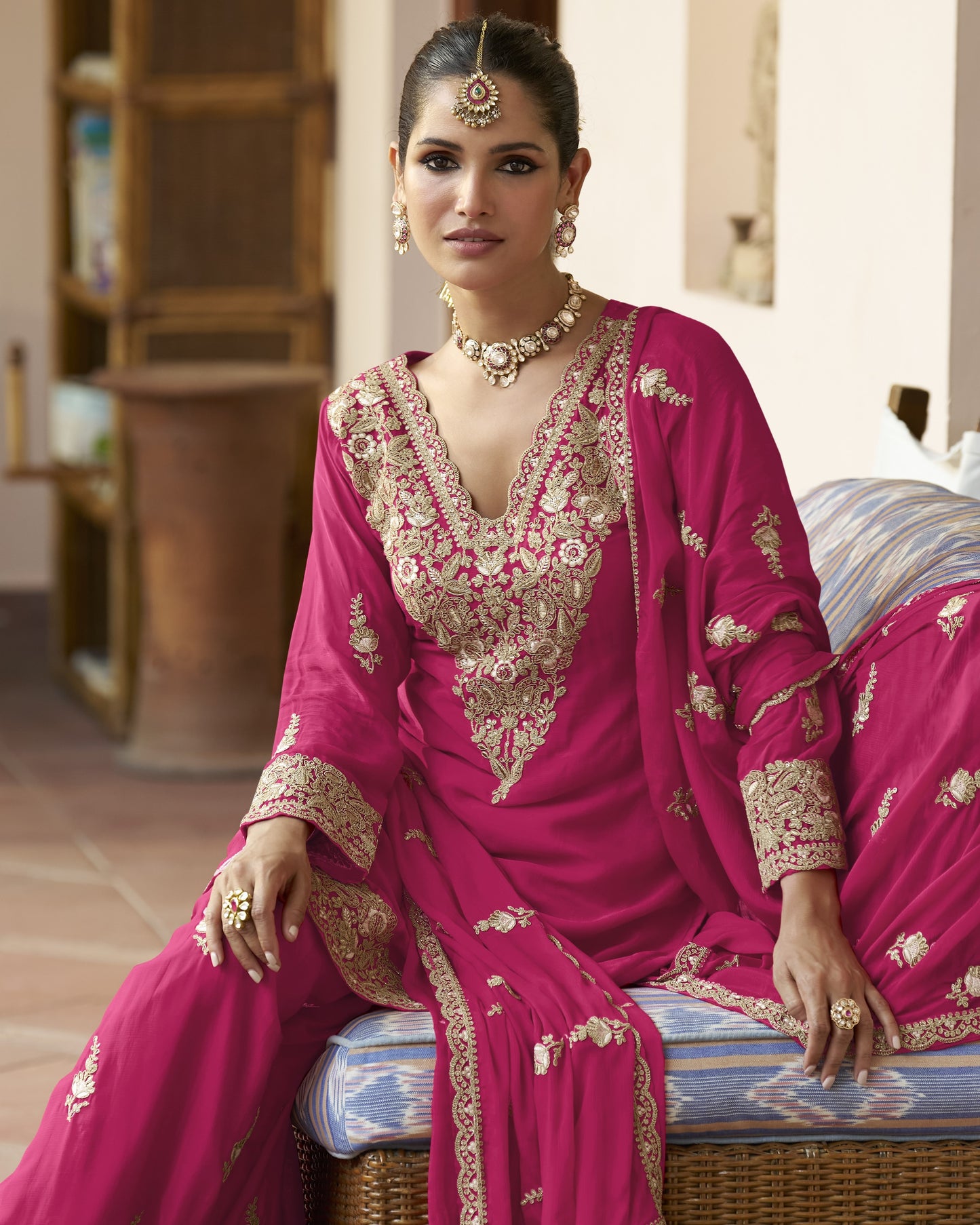 Woman in a traditional pink embroidered outfit sitting on a couch.