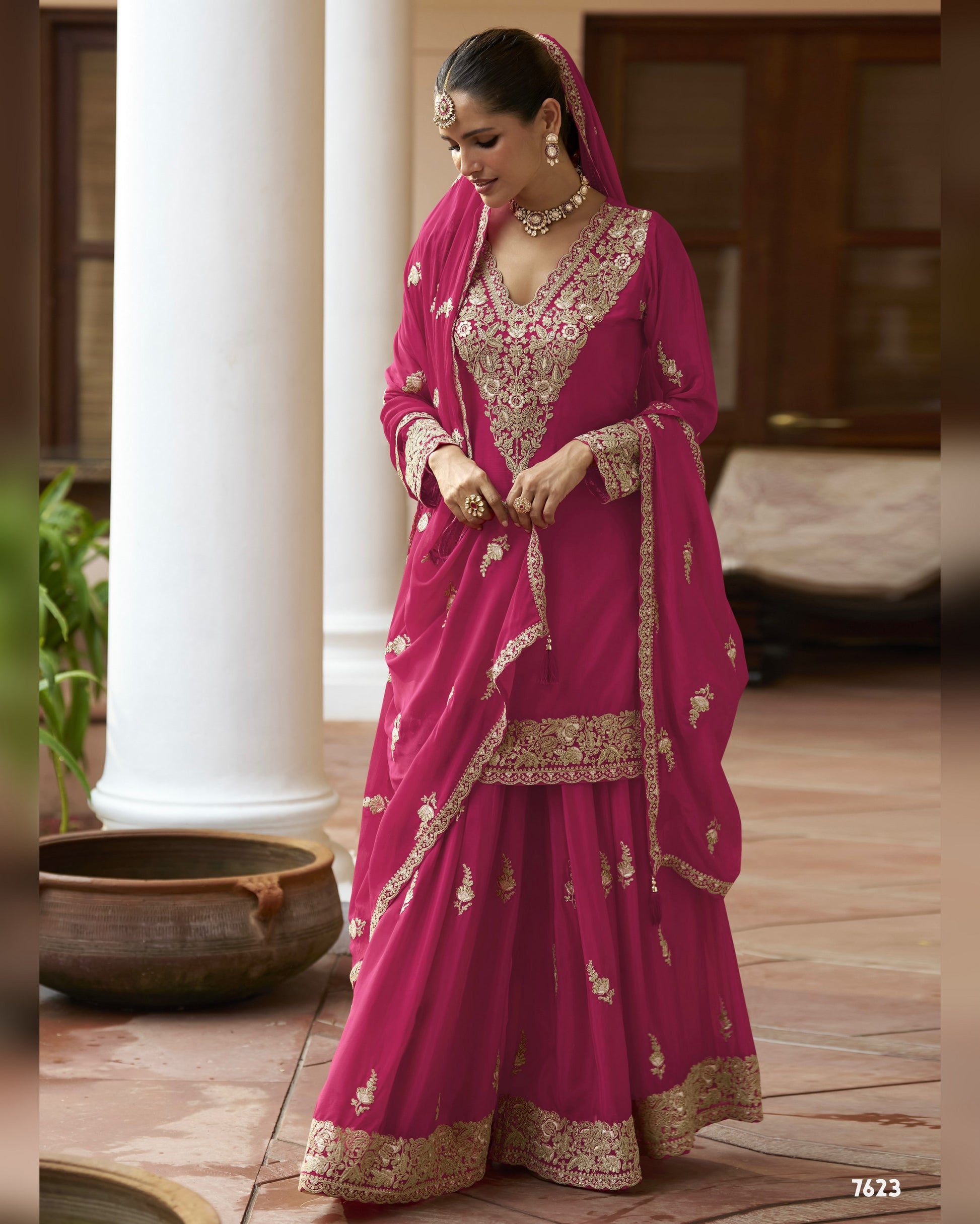 Woman in a traditional pink and gold saree with a blurred background