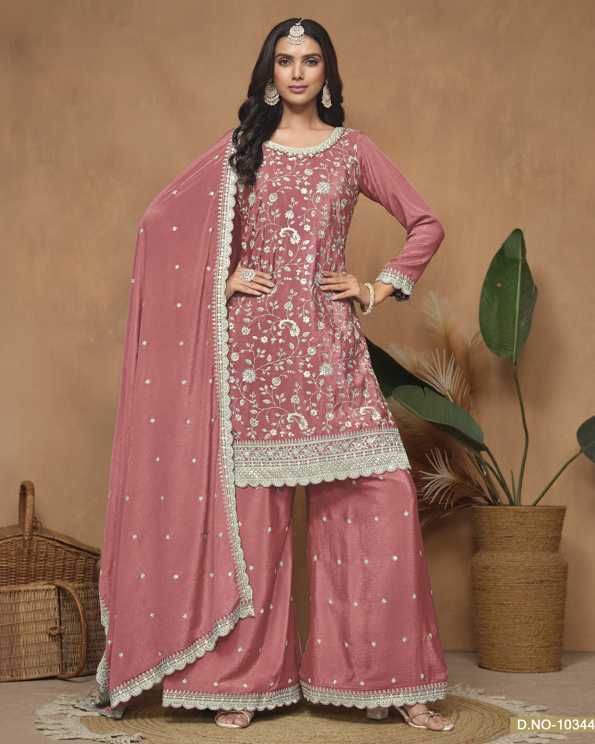 Woman wearing a pink traditional outfit with a matching dupatta against a beige background