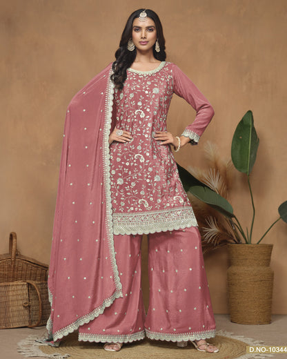Woman wearing a pink traditional outfit with a matching dupatta against a beige background