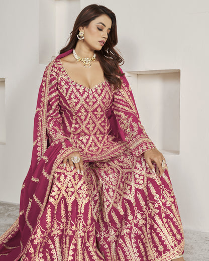 Woman in a traditional embroidered pink and gold outfit against a white background