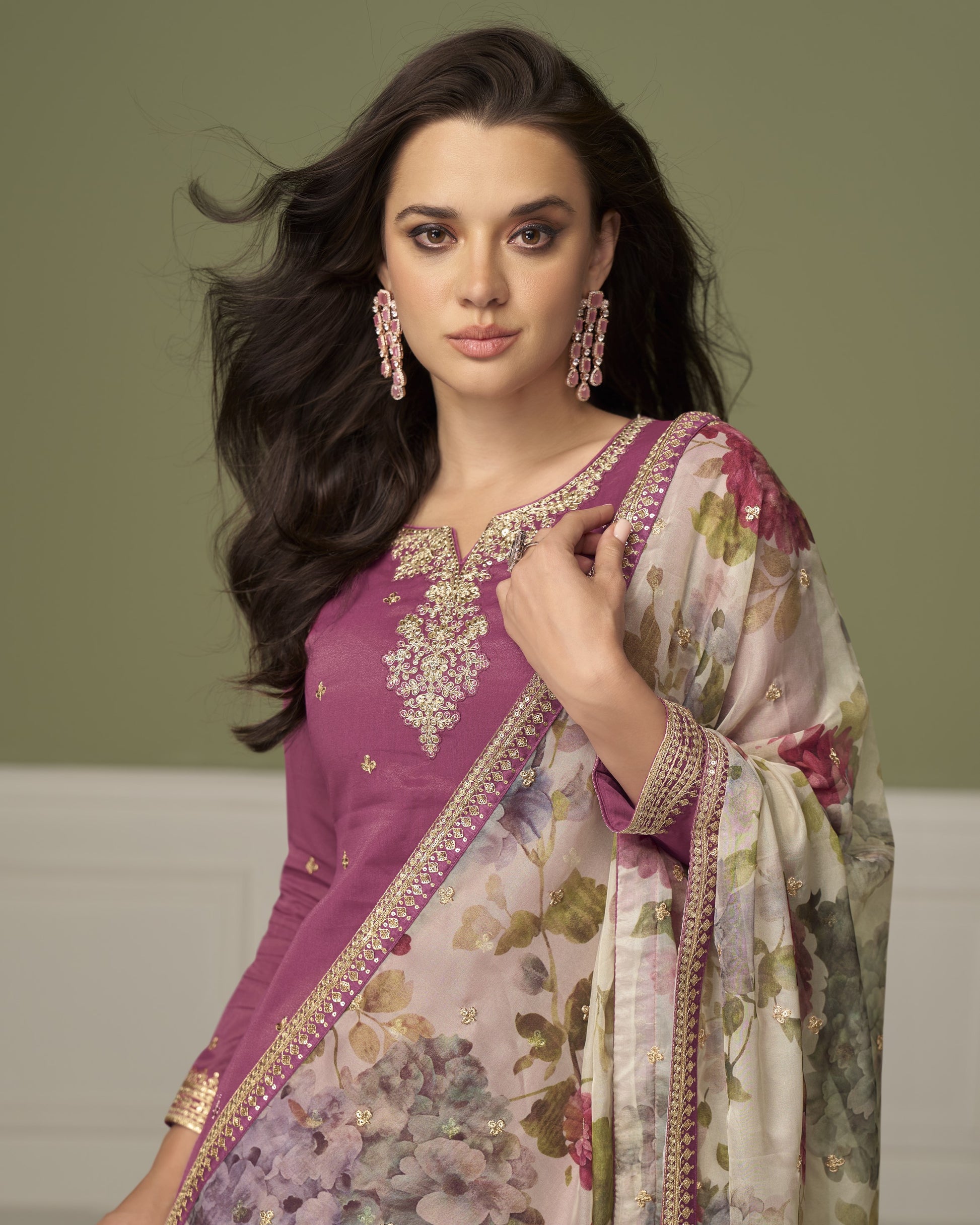 Woman wearing a traditional outfit with a floral pattern against a plain background