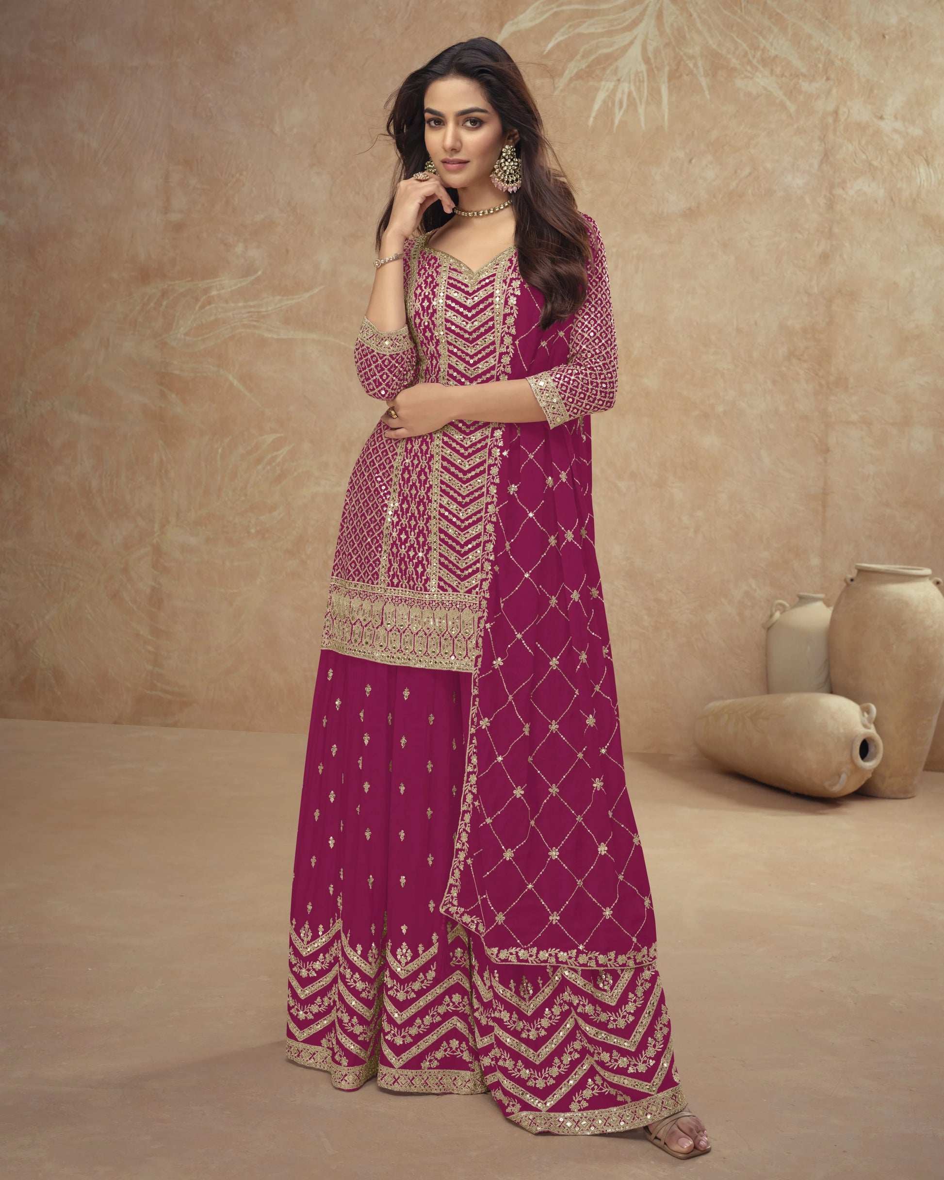Woman in a pink and gold traditional outfit against a beige background