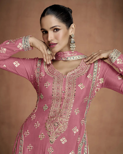 Woman wearing a pink embroidered traditional outfit with a brown background