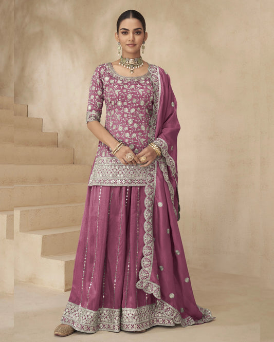 Woman in a traditional pink and silver embroidered outfit standing on a staircase.