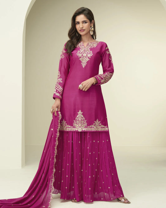 Woman wearing a pink traditional outfit with intricate embroidery on a neutral background