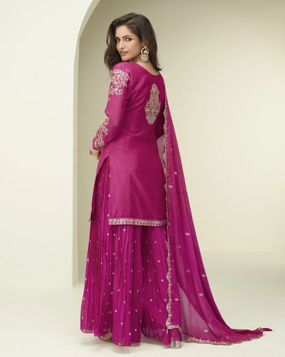 Woman wearing a pink traditional outfit with embroidery on a beige background