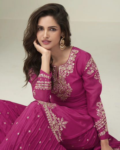 Woman wearing a pink embroidered traditional outfit with a neutral background