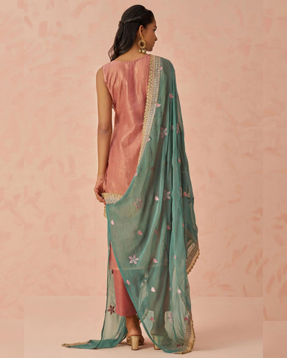 Woman wearing a pink saree with a green dupatta against a pink background