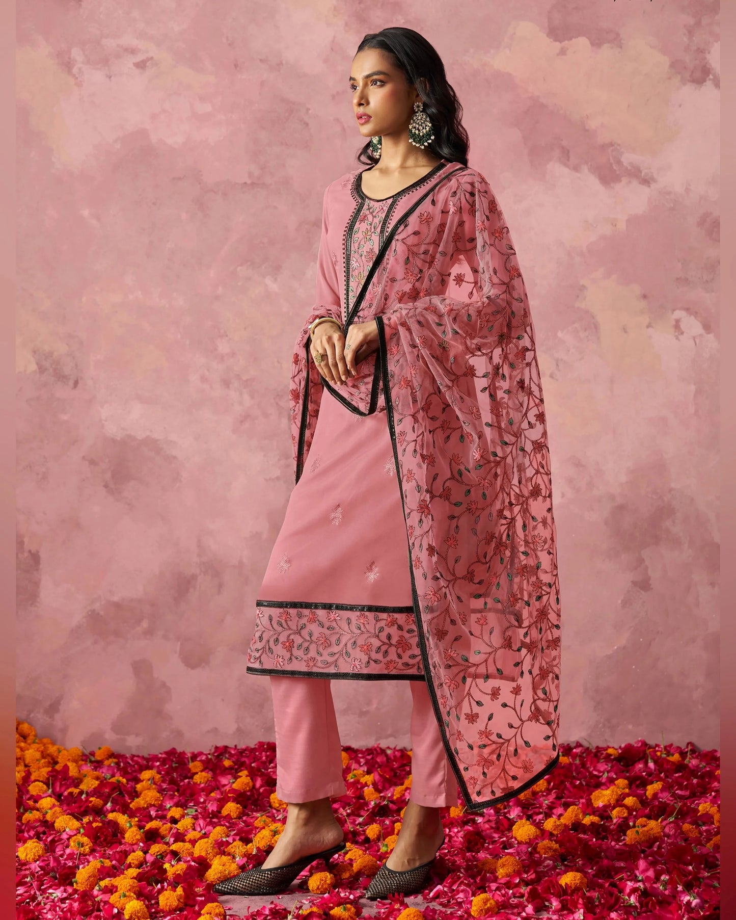 Woman in a pink traditional outfit with a floral pattern on a pink floral background