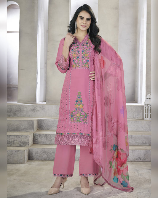 Woman wearing a pink embroidered outfit with a matching dupatta in an indoor setting.