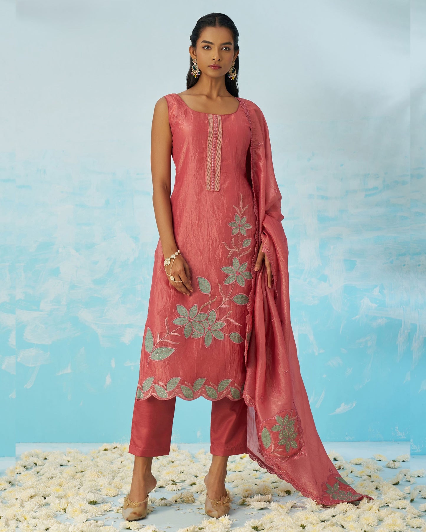 Woman wearing a pink traditional outfit with floral patterns against a light blue background.