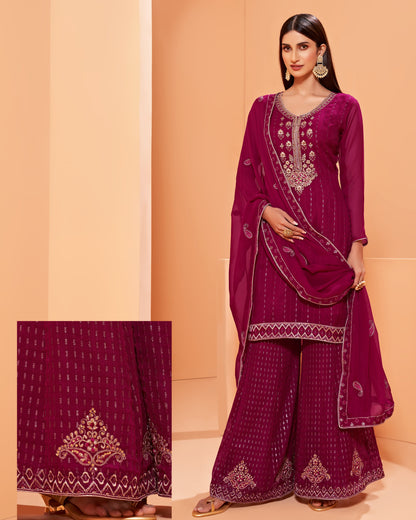 Woman wearing a purple embroidered traditional outfit with a matching dupatta on an orange background.