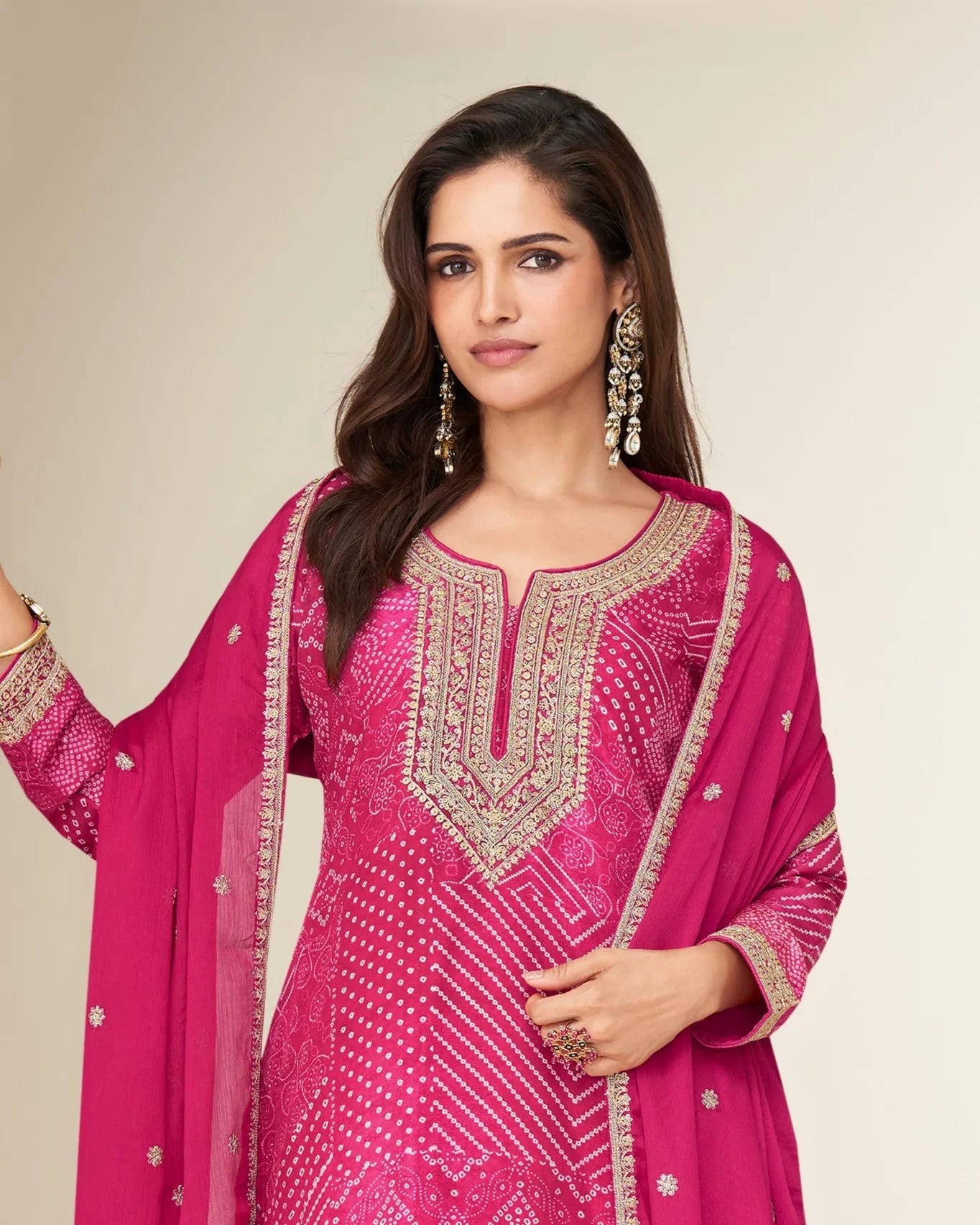 Woman wearing a pink embroidered traditional outfit with a plain background