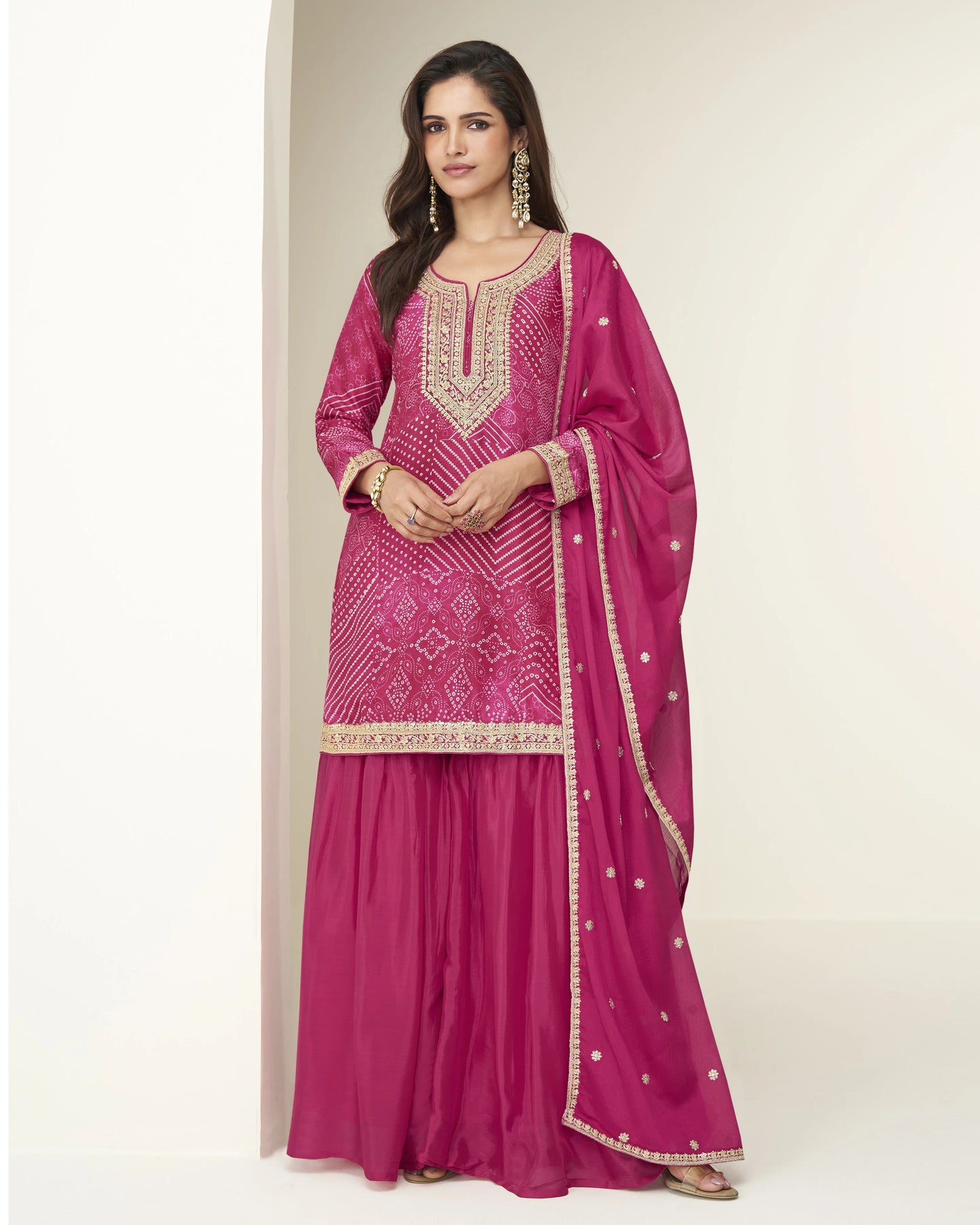 Woman wearing a pink traditional outfit with intricate designs on a plain background