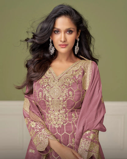 Woman wearing a traditional pink and gold embroidered outfit with a matching dupatta against a neutral background.