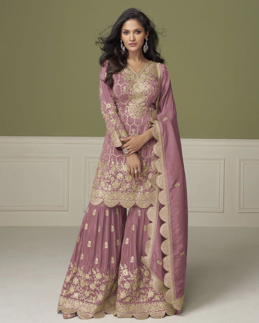 Woman wearing a traditional pink and gold embroidered outfit with a matching dupatta against a neutral background.