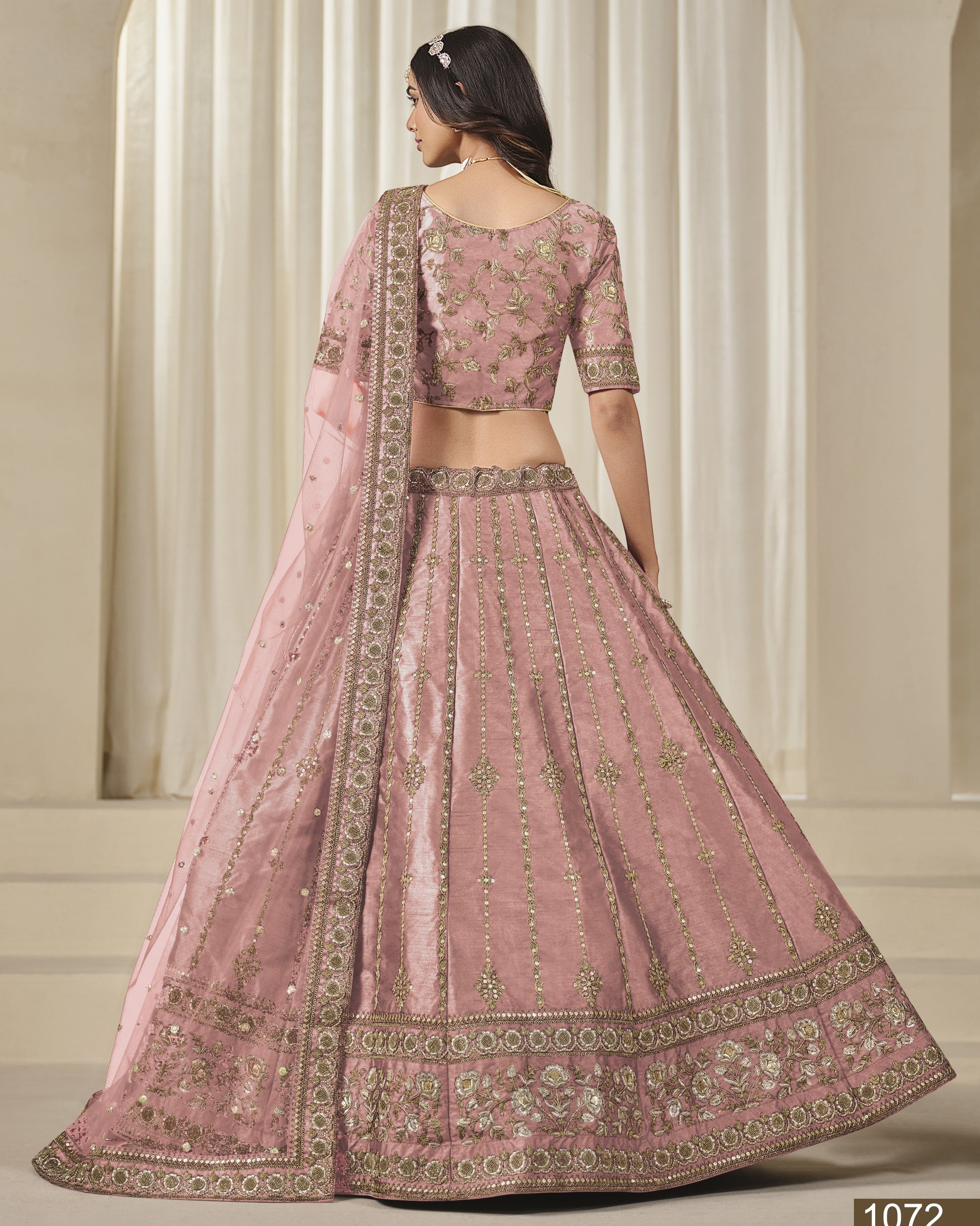 Pink embroidered traditional outfit with a white curtain background