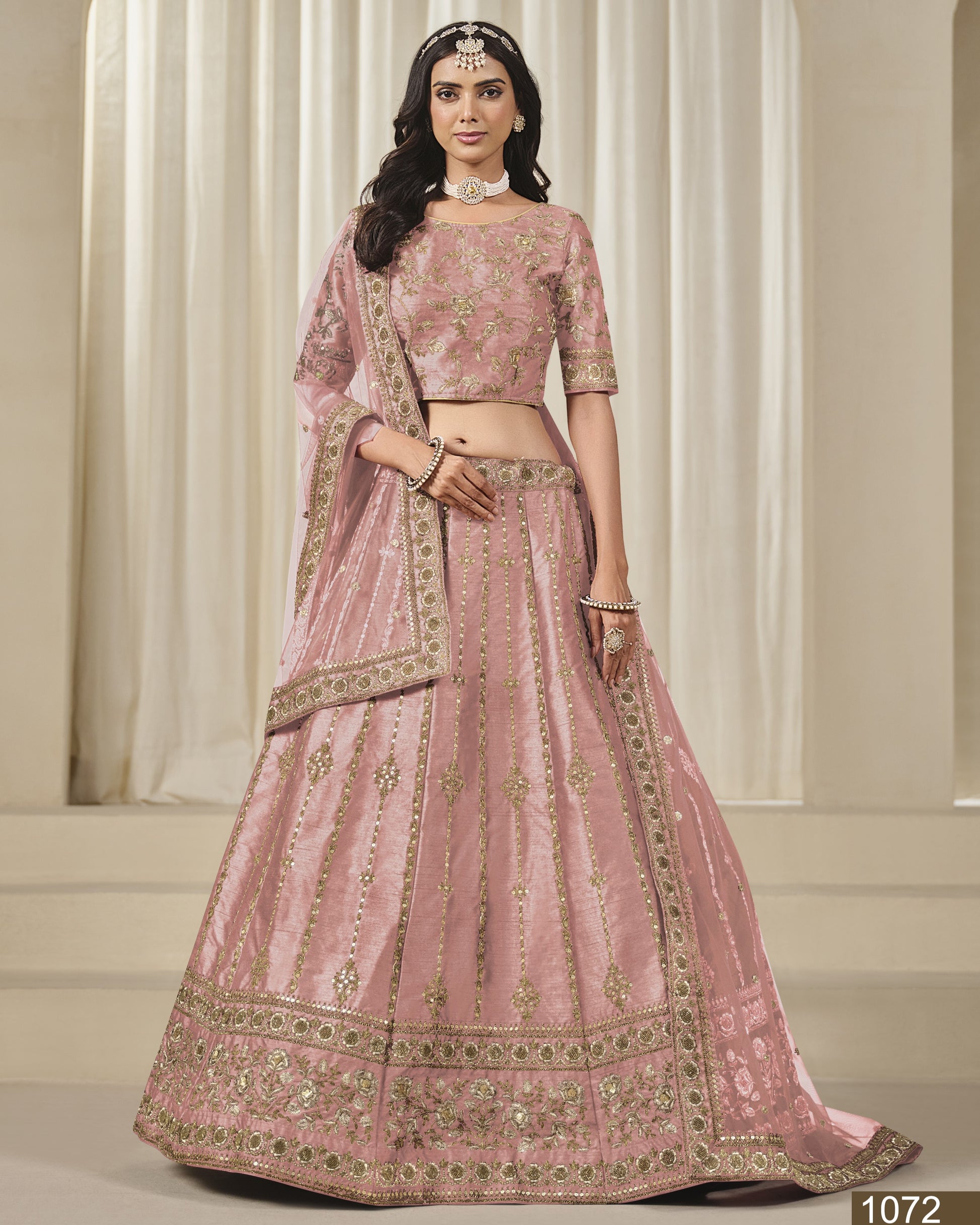 Woman wearing a pink embroidered traditional outfit against a neutral background