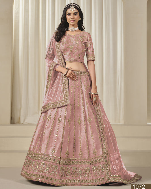 Woman wearing a pink embroidered traditional outfit against a neutral background