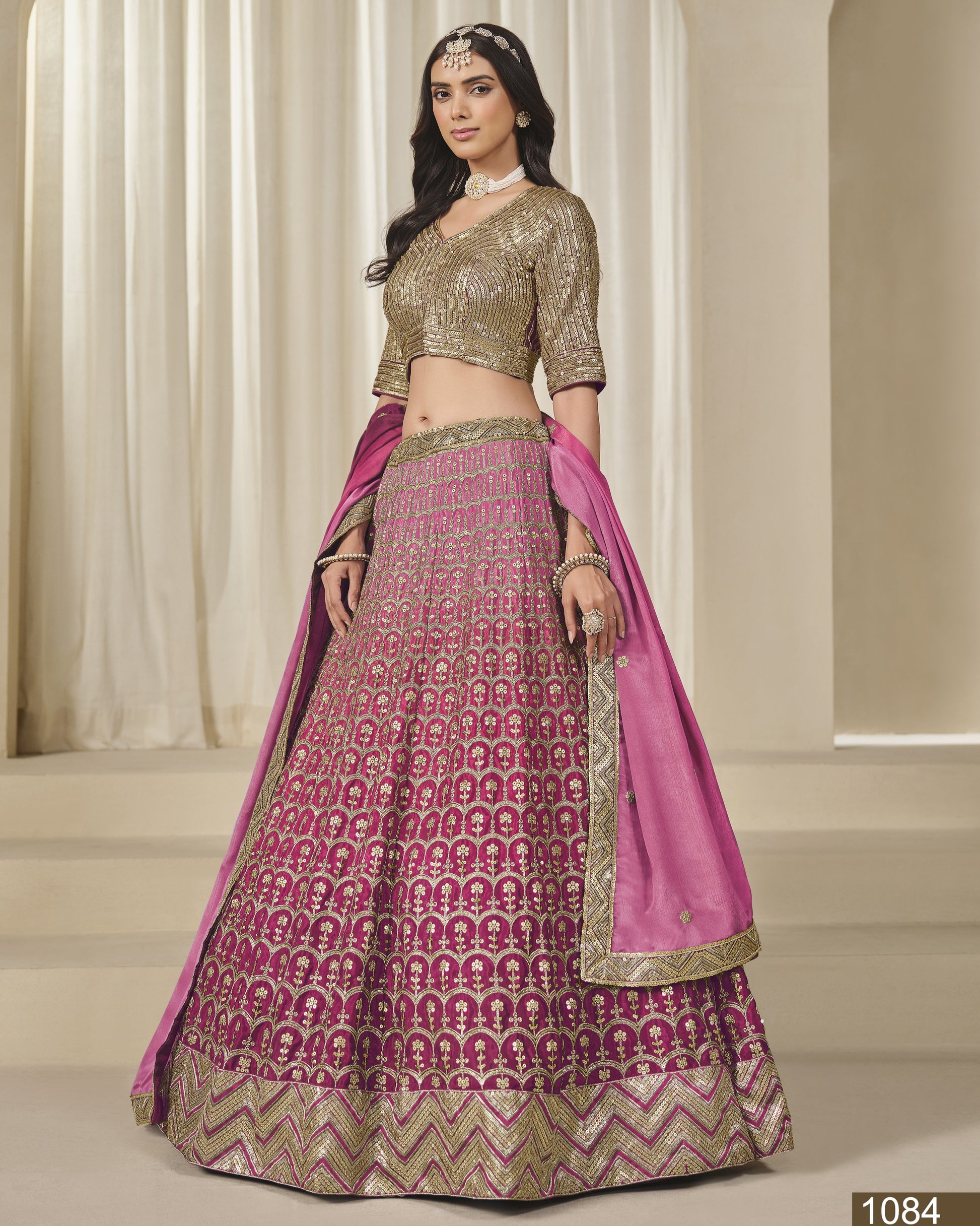 Woman wearing a traditional outfit with a pink and gold lehenga and blouse.