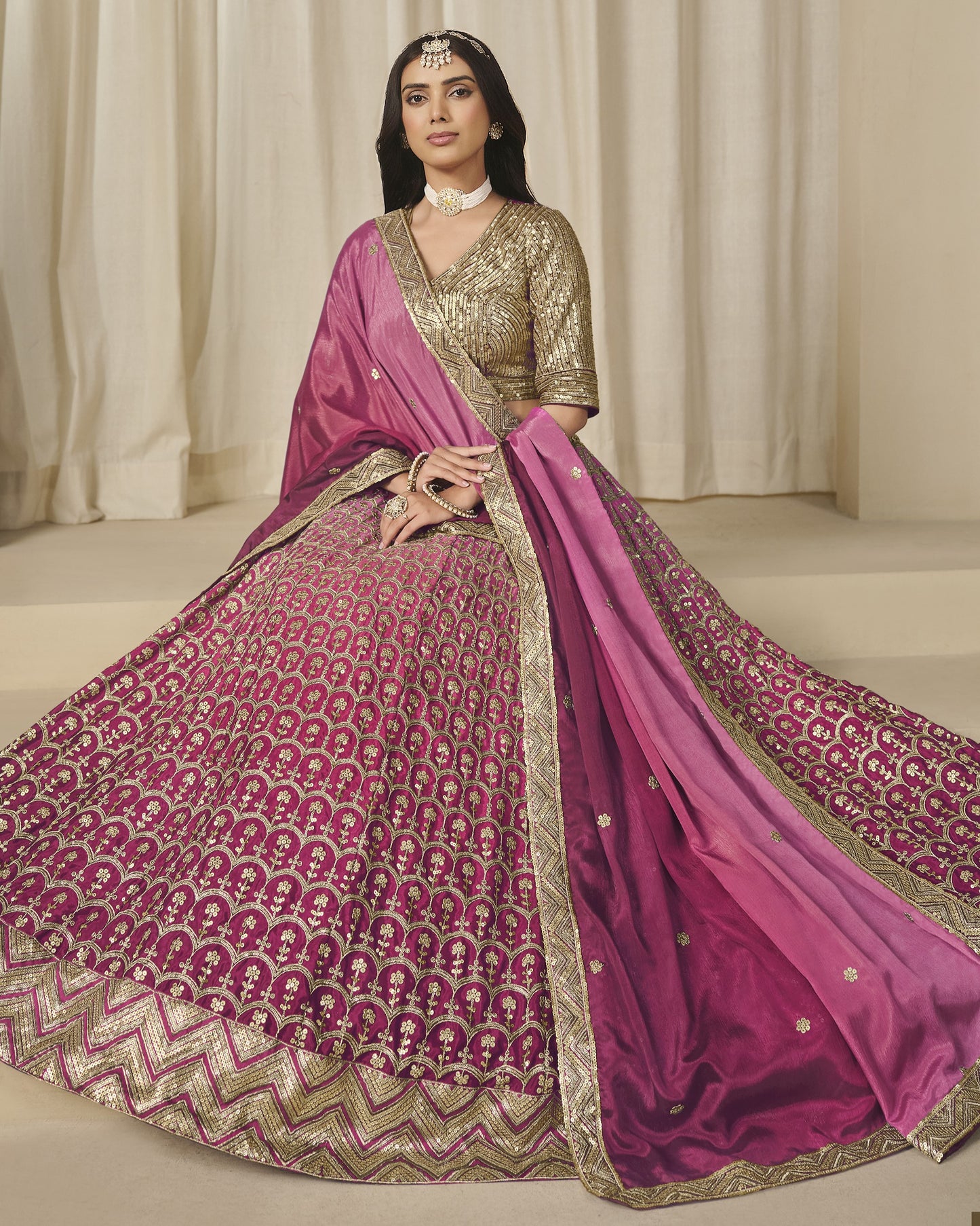 Woman wearing a traditional pink and gold saree with a matching blouse against a neutral background