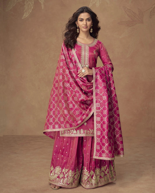 Woman wearing a pink traditional outfit with intricate patterns on a brown background