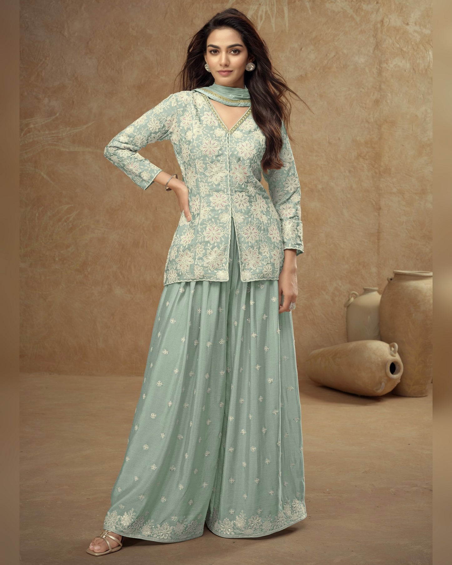 Woman wearing a light green traditional outfit with floral patterns against a beige background