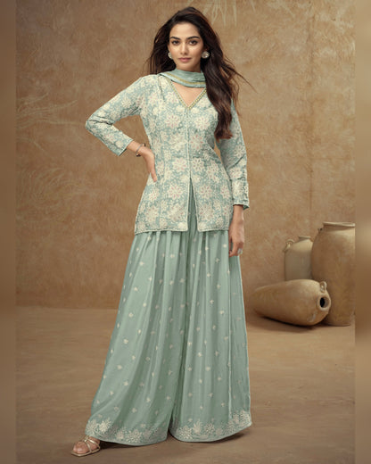 Woman wearing a light green traditional outfit with floral patterns against a beige background