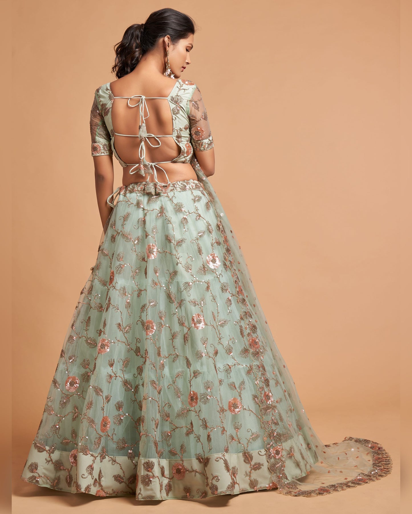 Woman wearing a floral embroidered lehenga on a beige background