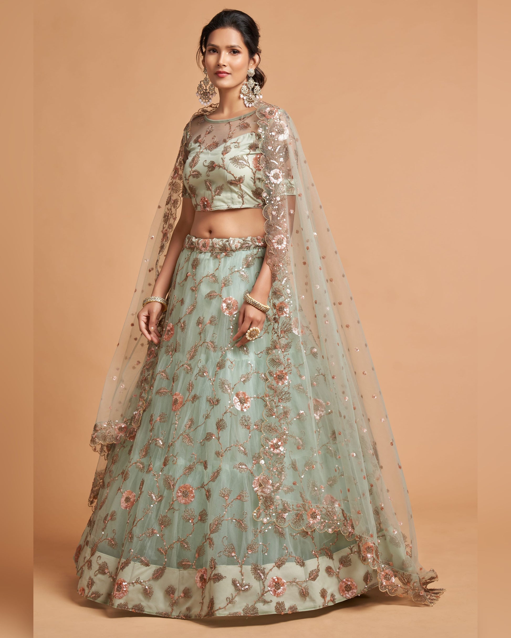 Woman wearing a light blue floral embroidered lehenga with a beige background
