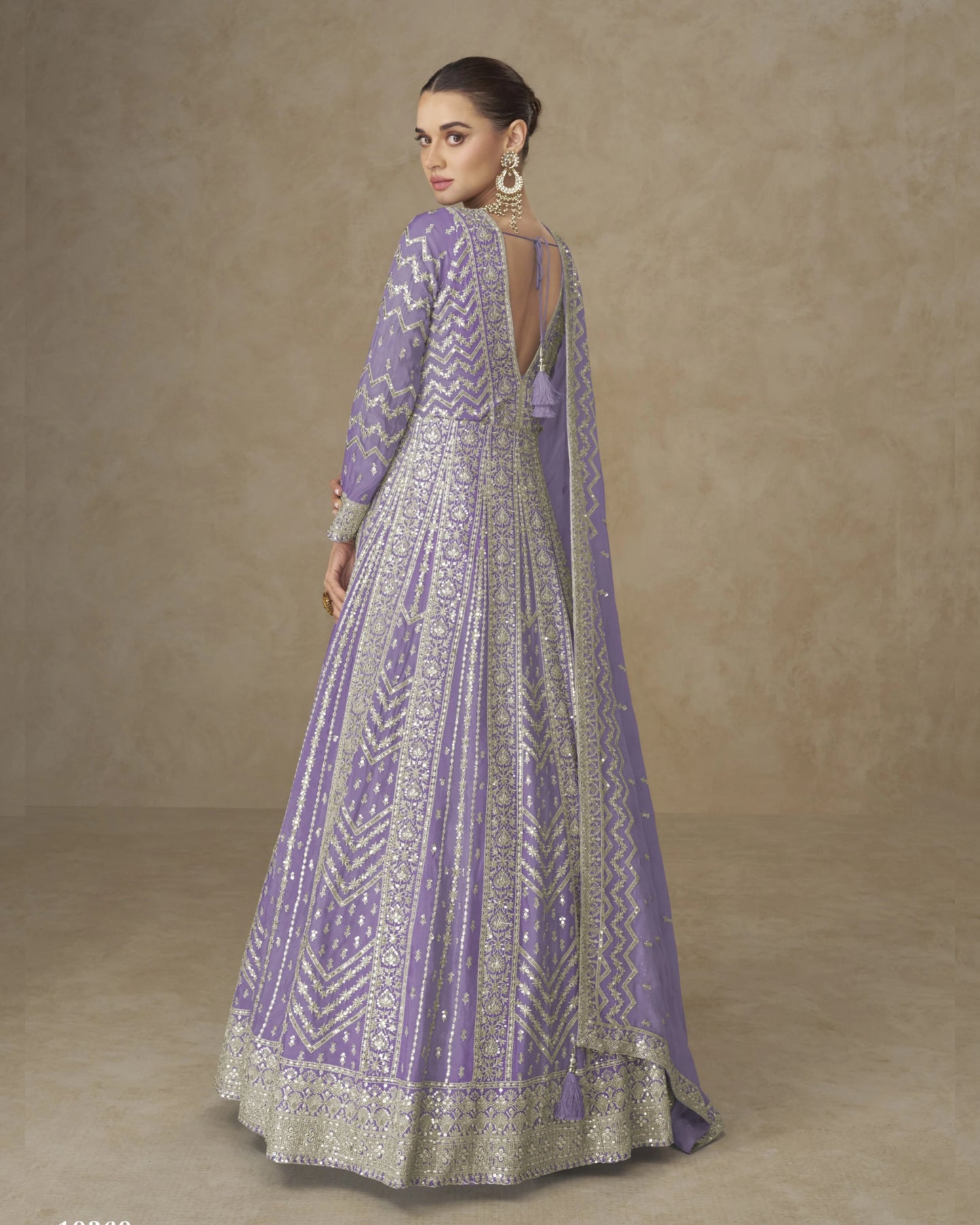 Woman wearing a purple and gray patterned dress against a beige background