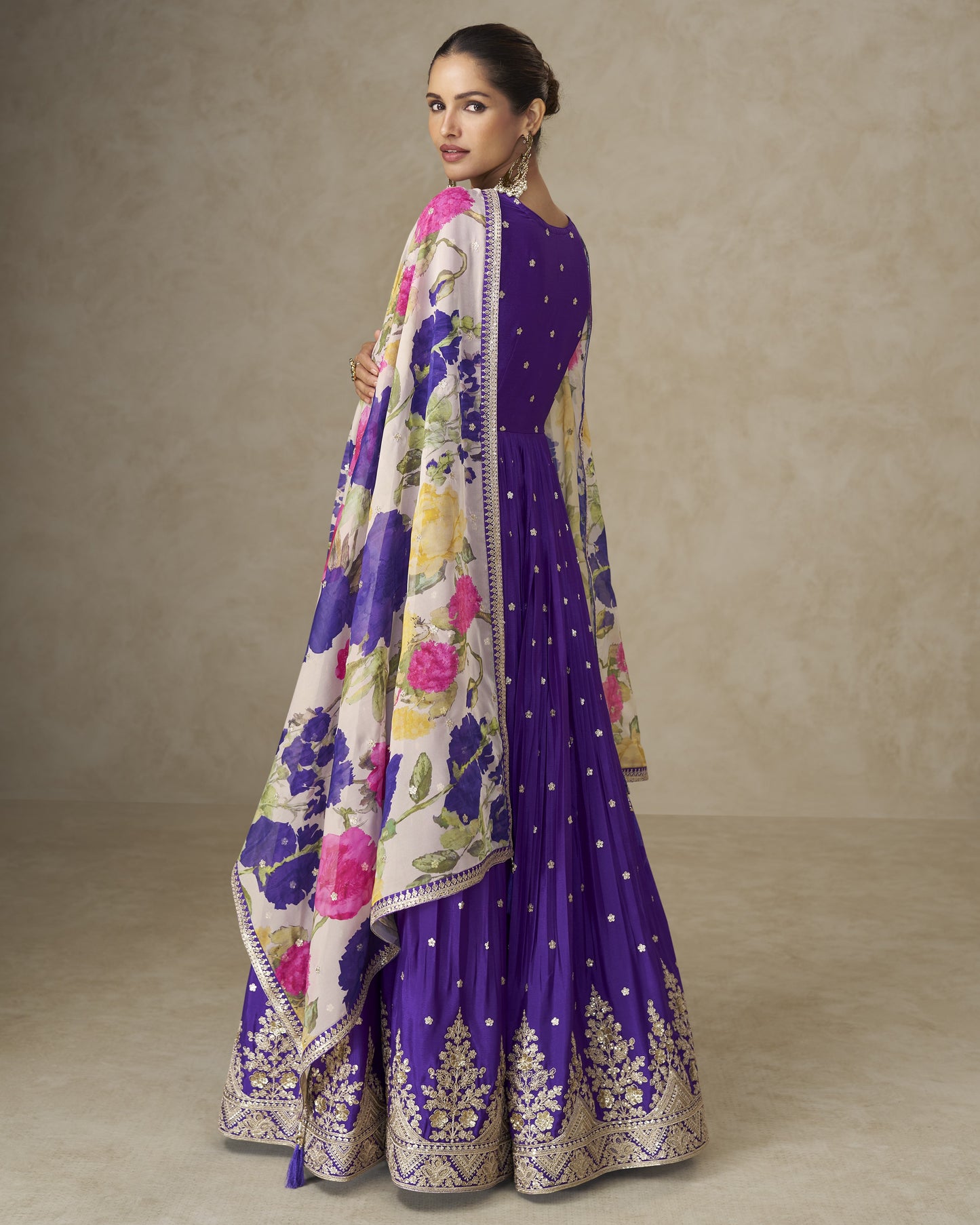 Woman wearing a purple traditional outfit with floral patterns on a neutral background
