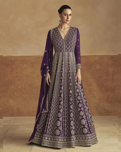 Woman wearing a purple and white patterned dress against a beige wall.