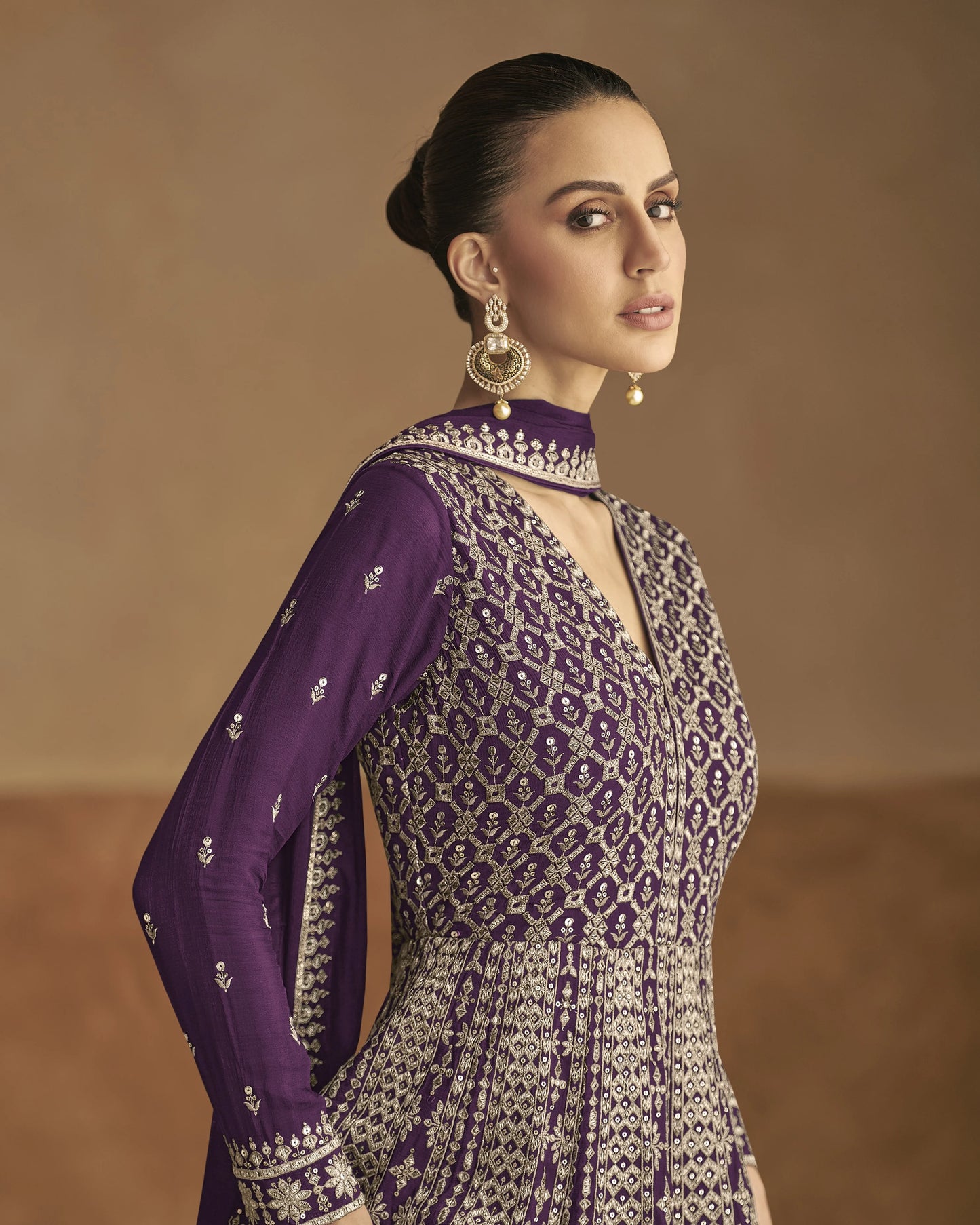 Woman wearing a purple and white patterned outfit against a brown background