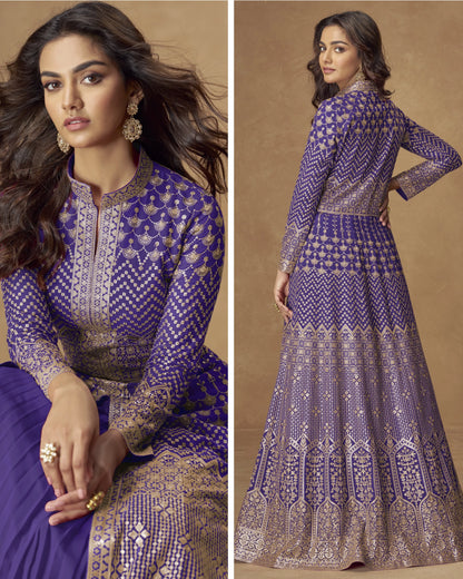 Woman wearing a purple and gold traditional outfit with intricate patterns, sitting and standing against a beige background.