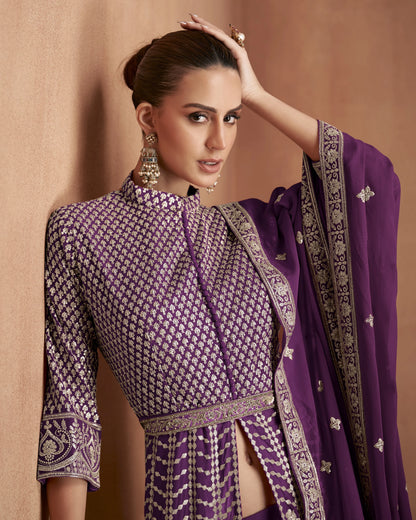 Woman in a traditional purple and black outfit with intricate patterns against a beige background