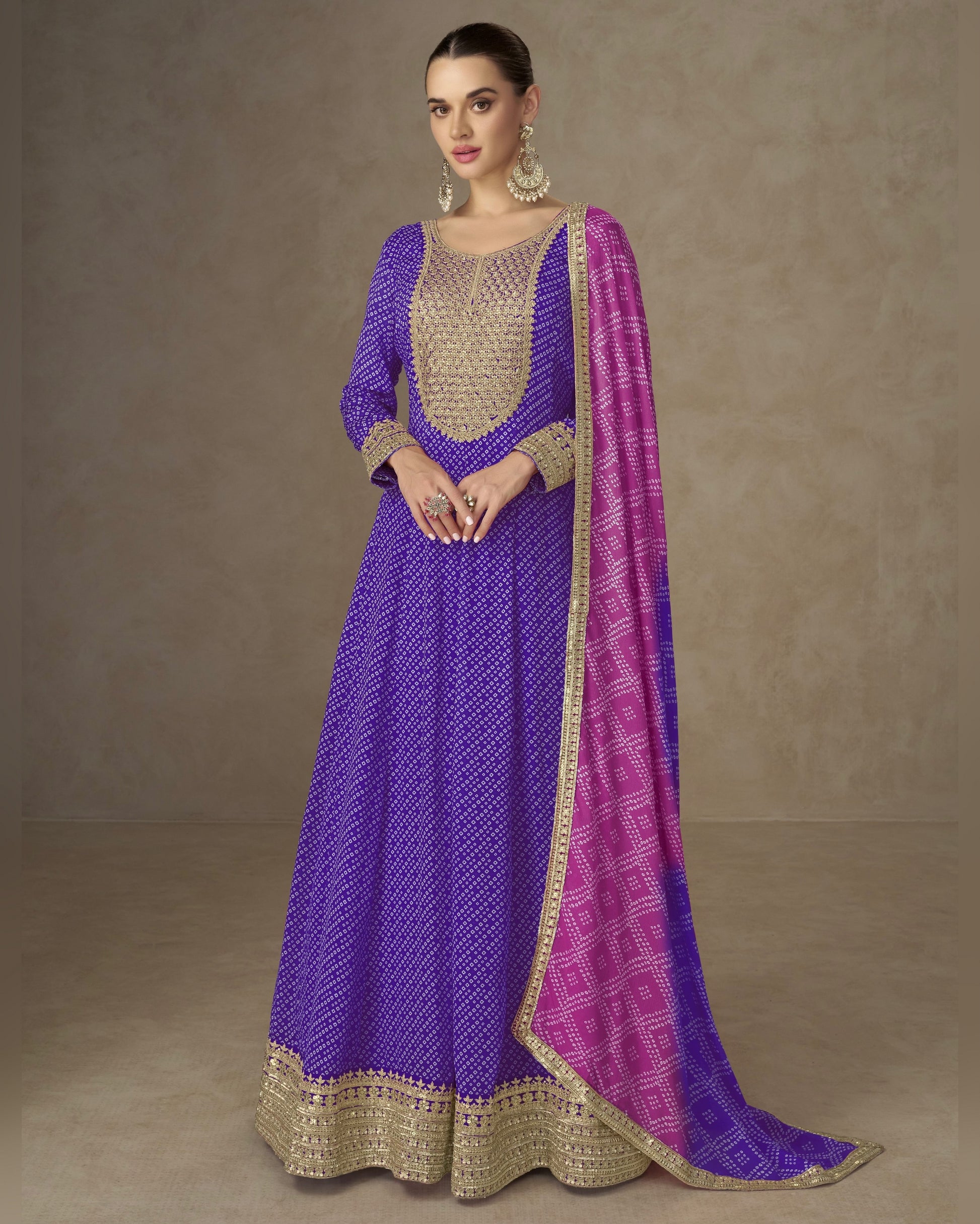 Woman wearing a purple and pink traditional outfit with gold detailing on a beige background