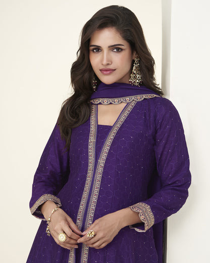 Woman wearing a purple traditional outfit with gold embroidery against a white background