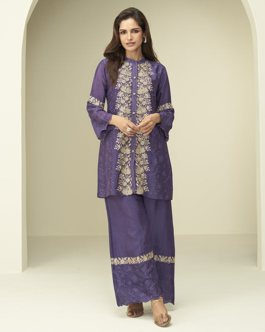 Woman wearing a purple embroidered outfit in a neutral setting