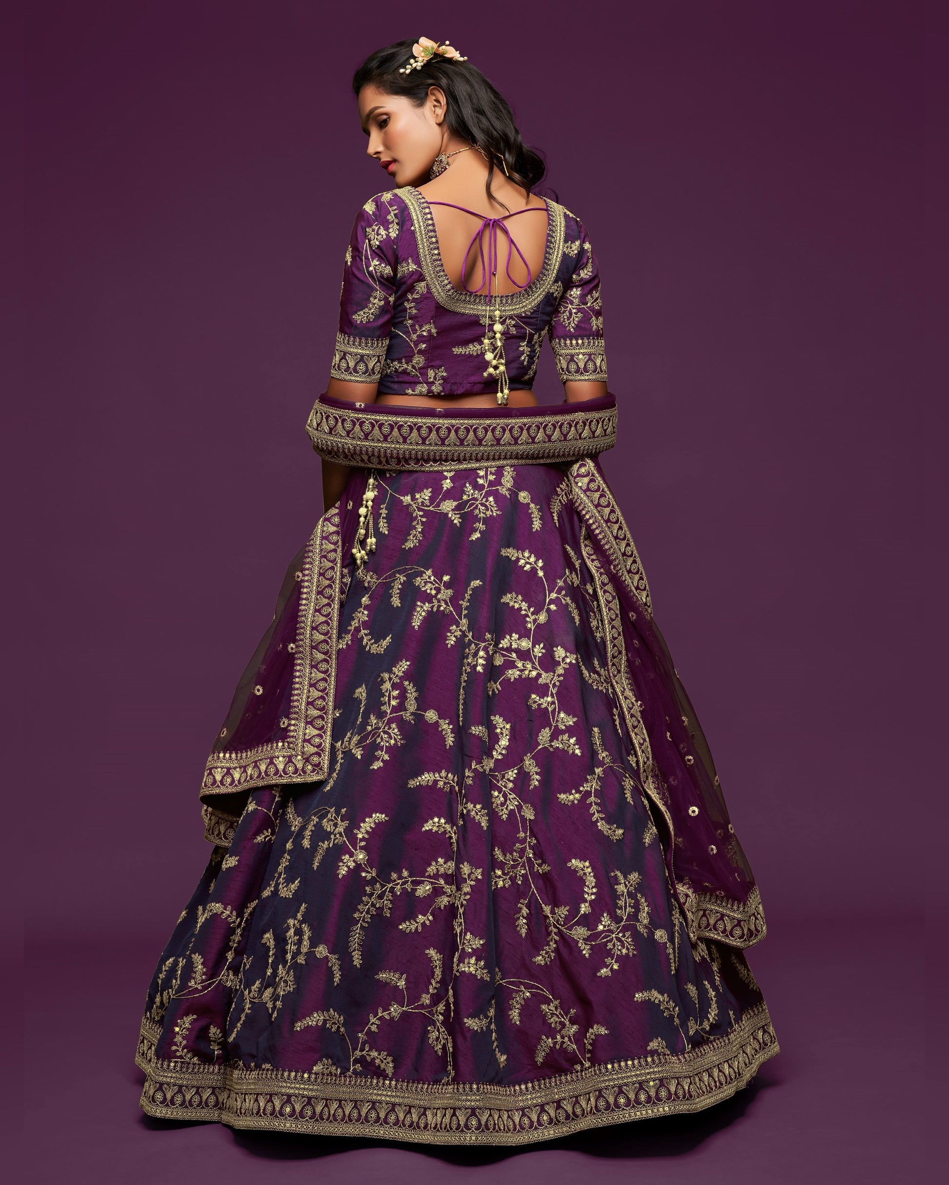 Woman wearing a purple embroidered traditional outfit on a purple background