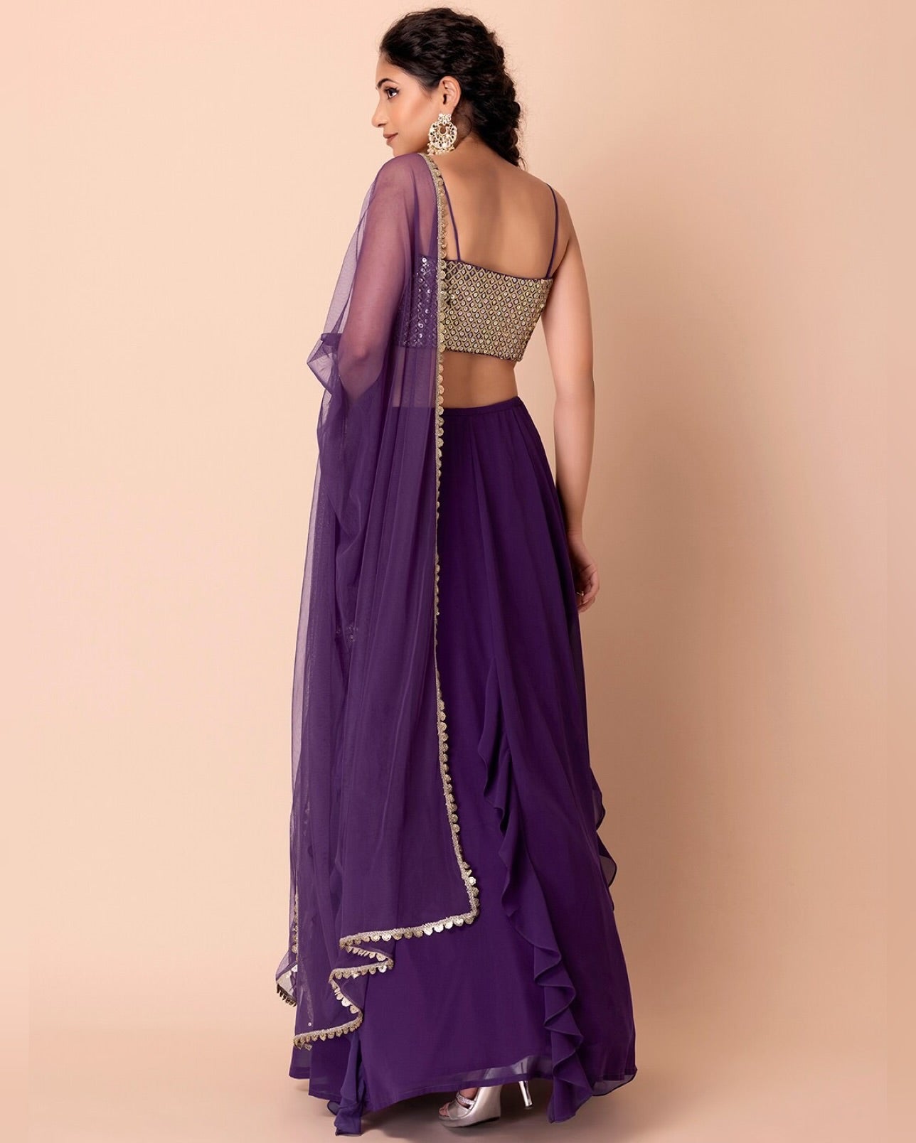Purple saree with gold border worn by a model on a beige background