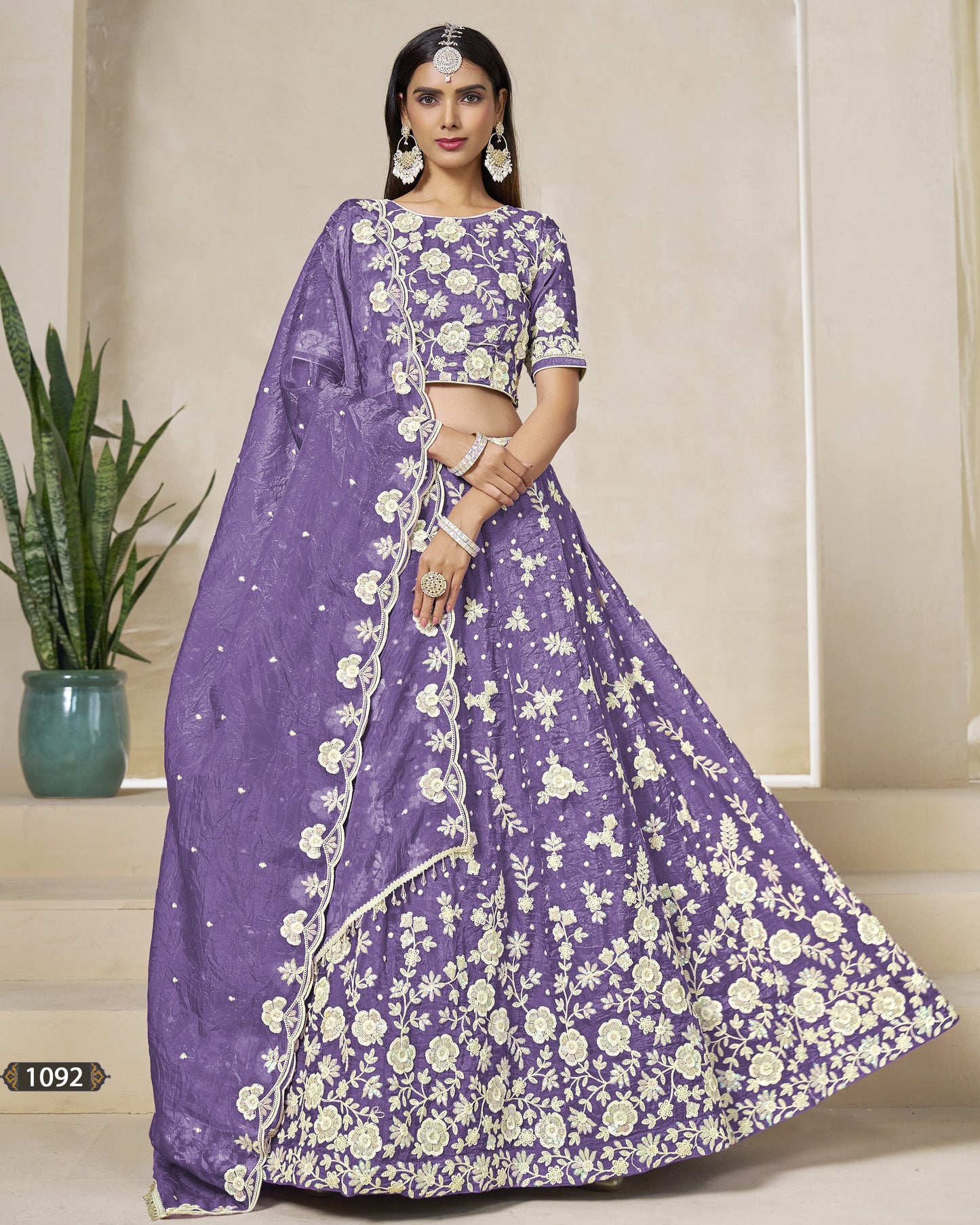 Woman wearing a purple saree with white floral patterns in an indoor setting.