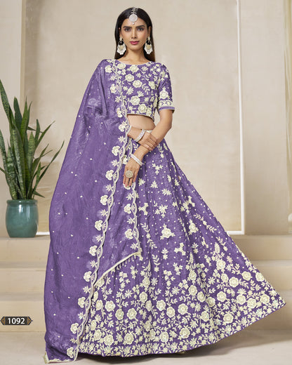Woman wearing a purple saree with white floral patterns in an indoor setting.
