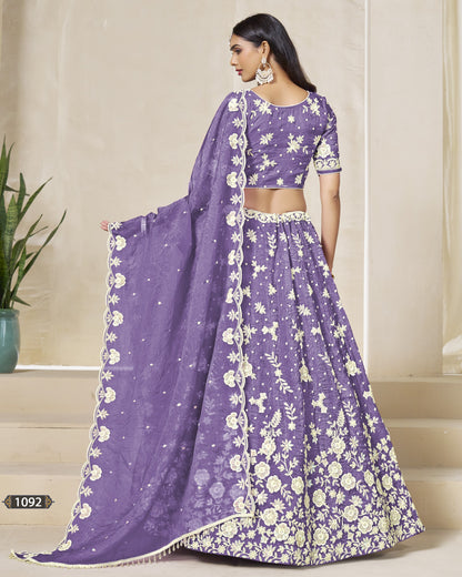 Woman wearing a purple floral lehenga with a matching blouse, standing indoors.
