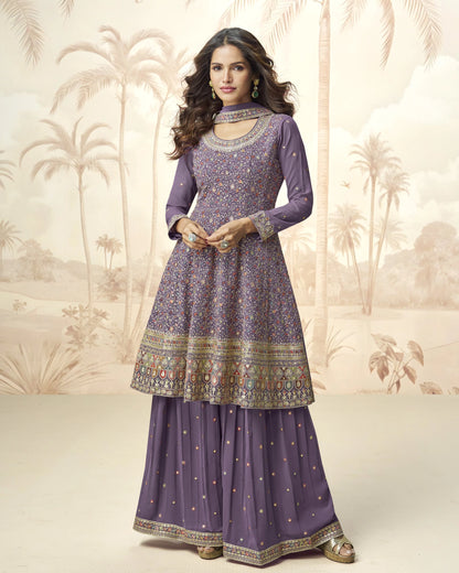 Woman wearing a purple traditional outfit with intricate patterns against a decorative background