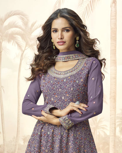 Woman wearing a purple traditional outfit with intricate designs against a beige background